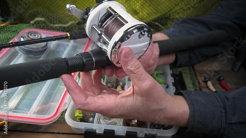 Wallpaper Mural Sport fishing equipment on a table in a studio composition, against a background of a net. A fisherman's hands check the tackle for use. Torontodigital.ca