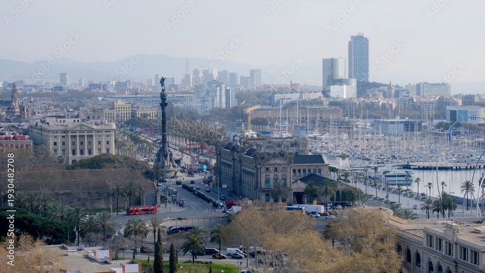 Obraz premium Barcelona cityscape with the columbus monument, bustling avenue and waterfront port vell marina filled with boats, historic buildings and hazy skyline by the sea