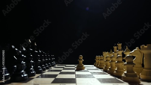 Chess pieces are facing each other on a black background. A close-up of a hand moving a white pawn 4 к