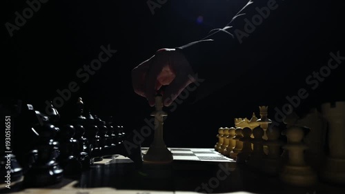 Chess pieces are facing each other on a black background. A close-up of a hand moving a white pawn 4 к