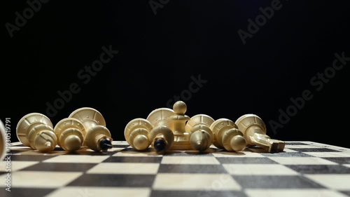 White chess pieces on a black background stand in a row, and the chess player's hand passes over them, knocking them down onto the game board. 4к