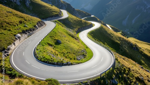 Aerial view of a winding mountain road with sharp hairpin turns surrounded by green grassy hills.