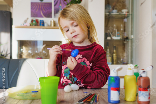 Child decorating colorful Easter eggs at home
