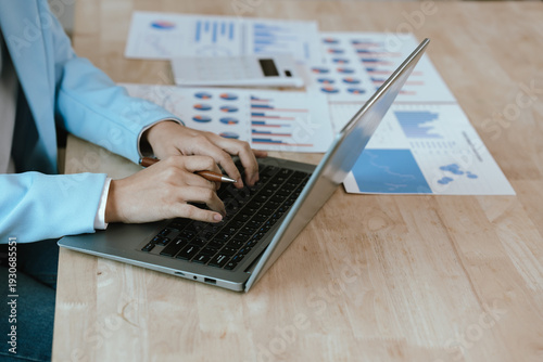 Close-up of businesswoman analyzing financial charts on clipboard with calculator and laptop, highlighting data review, budgeting, accounting, and strategic business planning.
