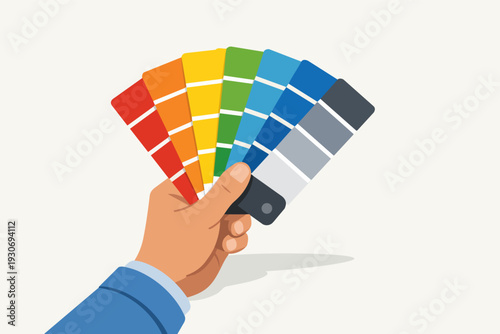 Hand holding a color palette fan, selecting paint swatches for creative design
