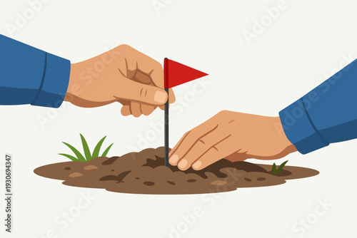 Two hands planting a red flag in a small mound of soil with green grass