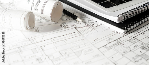 Architectural blueprints with rolled plans and solar panel, sustainable architecture and green building design, renewable energy integration, construction planning background.