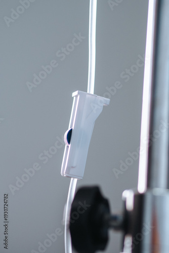 Φωτογραφία This vertical shot focuses on a white plastic roller clamp attached to a clear intravenous IV tube