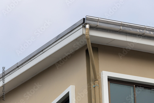 Фотография A building with a brown and metal rain gutter and dark sky