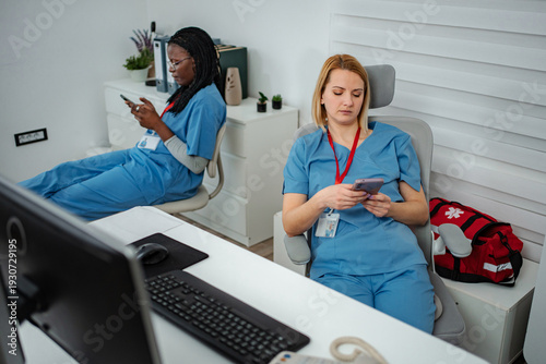 Cuadro en lienzo Nurses scrolling on smartphones ignoring work in office