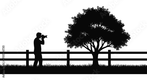 A photographer stands with camera near a tree and fence creating a striking black silhouette high quality professional detailed modern elegant