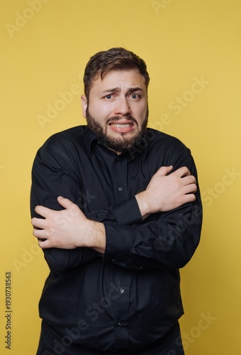 Bilde på lerret Uneasy mood captured in bright yellow background as man expresses his discomfort