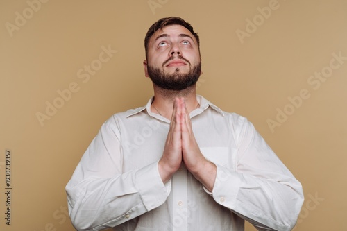 Obraz na plátně Man expressing gratitude with hands clasped together in a serene, warm-toned set