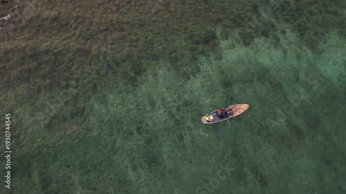 Aerial drone view of a person paddleboarding on a stand up paddle board in the tropical ocean of Sri Lanka. Turquoise water, calm waves, active lifestyle and exotic travel destination