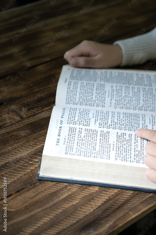 Naklejka premium Hand Reading Holy Bible on Wooden Table