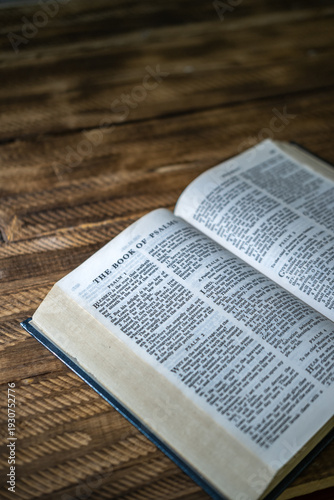 Open Holy Bible placed on rustic wooden table with natural light and copy space. Concept of Christianity, faith, spirituality, devotion, and religion.
