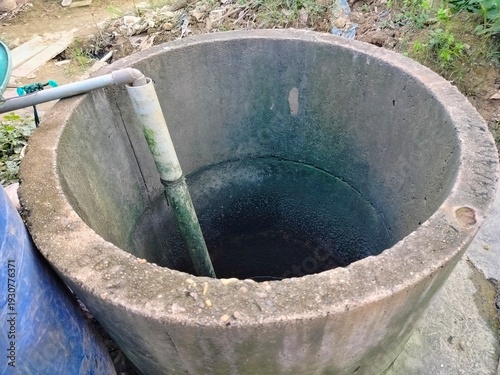 mossy concrete water well with PVC pipe in outdoor area
