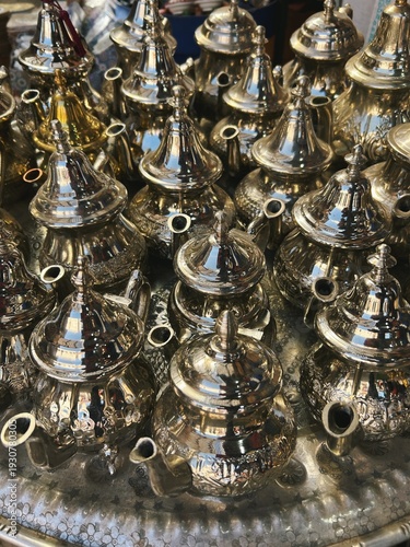 Handcraft silver oriental teapots to drink traditional moroccan tea, made of steel and popular tourist art souvenir at local street souk market (bazaar) in arabic medina of Marrakech, Morocco, Africa.