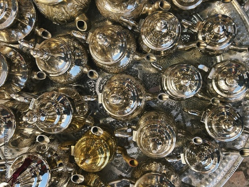 Handcraft silver oriental teapots to drink traditional moroccan tea, made of steel and popular tourist art souvenir at local street souk market (bazaar) in arabic medina of Marrakech, Morocco, Africa.