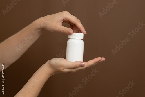 Human hands holding blank white medicine bottle packaging