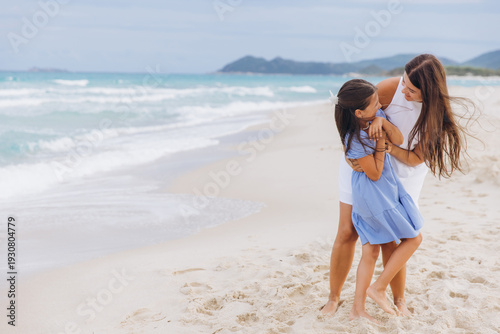 Foto Mother and daughter embracing and playing on a sandy beach, enjoying summer vaca