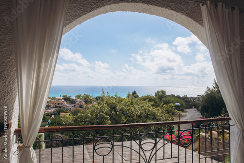 Balcony view over Costa Rei, Sardinia, Italy, Mediterranean sea with white curtains and clear sky