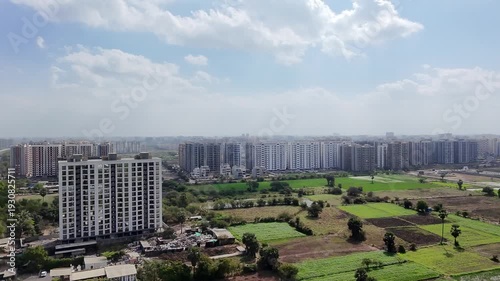 Modern cityscape with high-rise buildings and green fields under blue sky