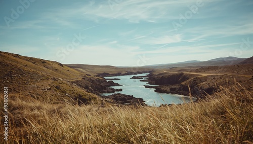 View of a River Flowing Through Rocky Land With Hills Under a Clear Sky
