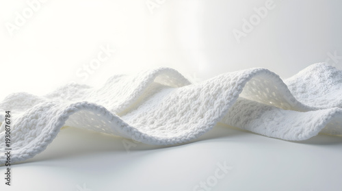 A soft, textured white towel elegantly drapes across a smooth surface, creating a serene and minimalist aesthetic.