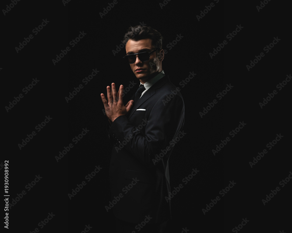 Obraz premium Confident man in suit with sunglasses posing with joined hands