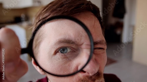 Close-up portrait of funny man looking through a magnifying glass. Concept of attention, investigation, analysis, curiosity, inspection, focus, detail search and critical observation.