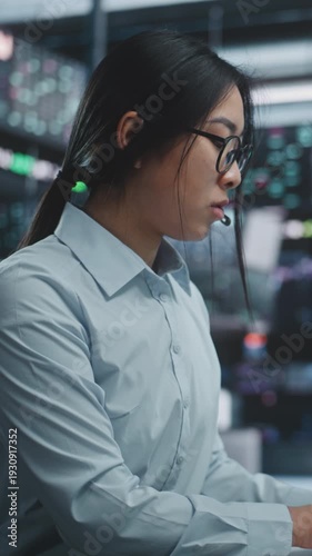 Female Trader Executing Stock, Cryptocurrency Deals in Digital Office. Focused Asian Broker Trading Global Assets Multi Monitor Workstation With Tablet. Professional Market Execution. Vertical Shot.