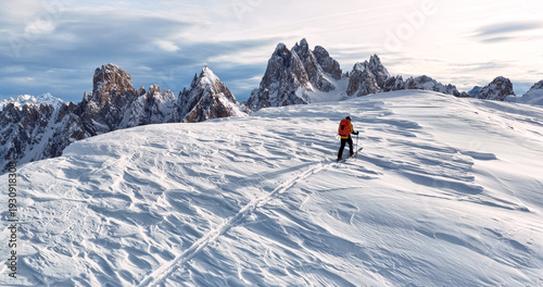 Photos Ski mountaineer crossing a snowy ridge in the Dolomites with dramatic alpine peaks and blue sky in the background, capturing winter adventure and breathtaking mountain landscape