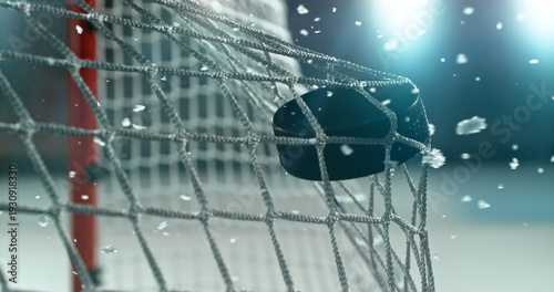 Action sports photo of a hockey puck flying into the goal net during a scoring shot, with ice particles in the air, capturing speed and intensity.