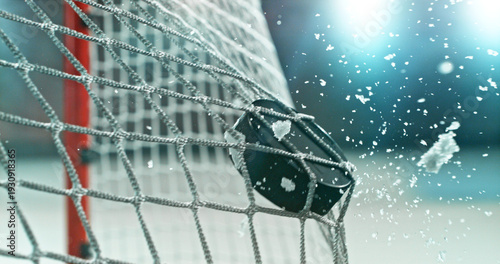 Photography Action sports photo of a hockey puck flying into the goal net during a scoring shot, with ice particles in the air, capturing speed and intensity