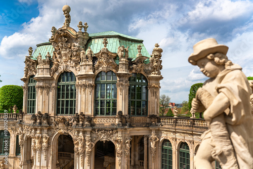 Wall pavilion of Dresden Zwinger in focus, baroque architecture with a sculpture softly blurred in the foreground, historic palace complex in Dresden, Germany.