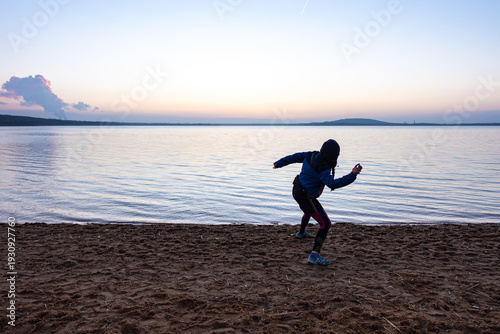 Blue hour at Störmthaler Lake near Leipzig, person skipping a stone across the water, smooth gradient from blue to violet in the evening sky.