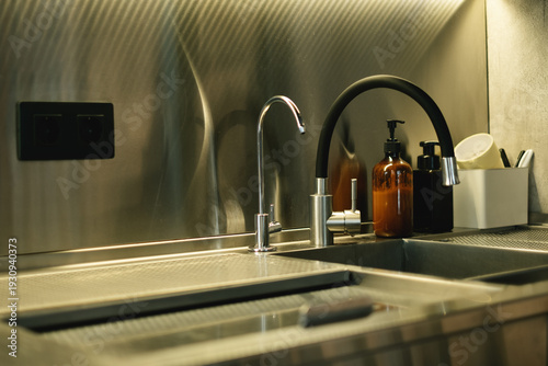 Modern kitchen corner with metal sink, dual water taps and wall outlets