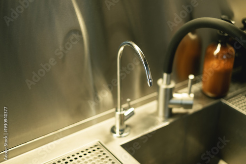 Close-up of dual kitchen faucets in modern metal sink