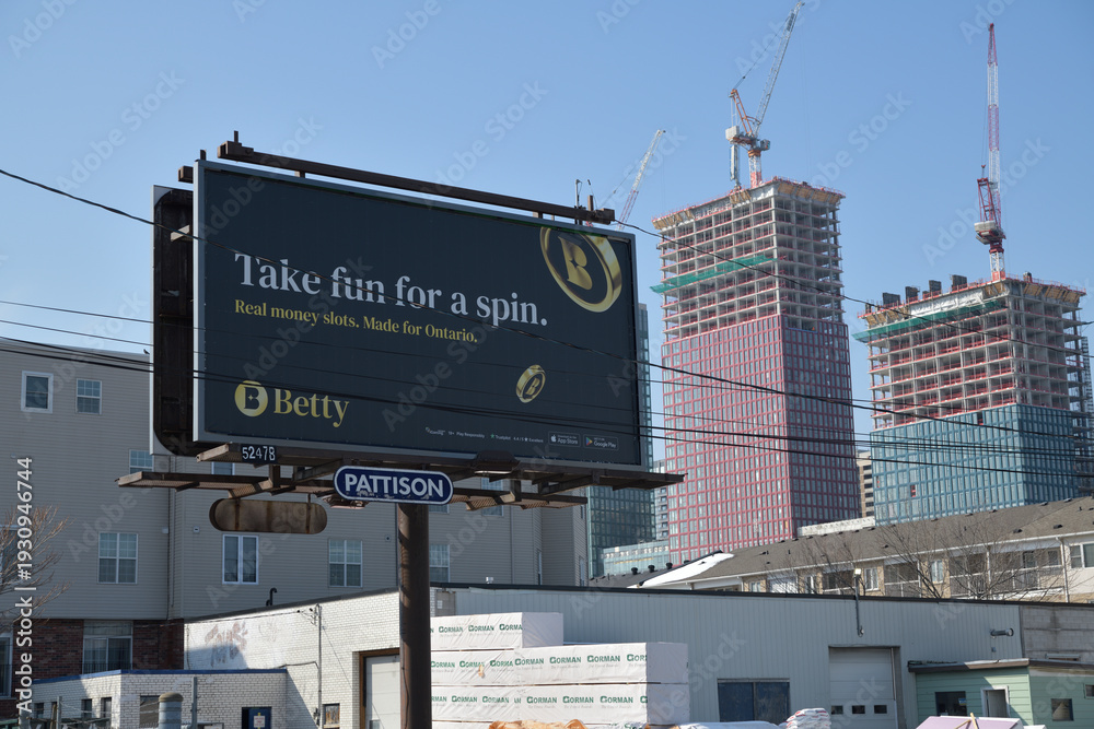 Fototapeta premium road side pylon billboard sign (with Betty ad) inside the Central Fairbank Lumber complex at 2296 Gerrard St E, Toronto (with view of Main Square redevelopment behind)