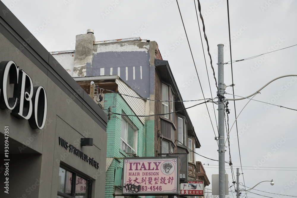 Naklejka premium old buildings near the intersection of Gerrard St E and Pape Av incl projecting signs for Italy Hair Design at 934 Gerrard St E, Toronto
