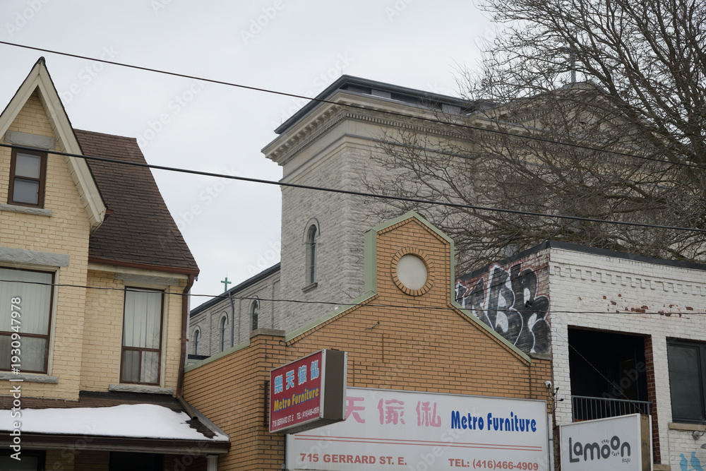Naklejka premium eclectic contrast of architectural styles including sign of Metro Furniture, a furniture store, located at 715 Gerrard St E, Toronto