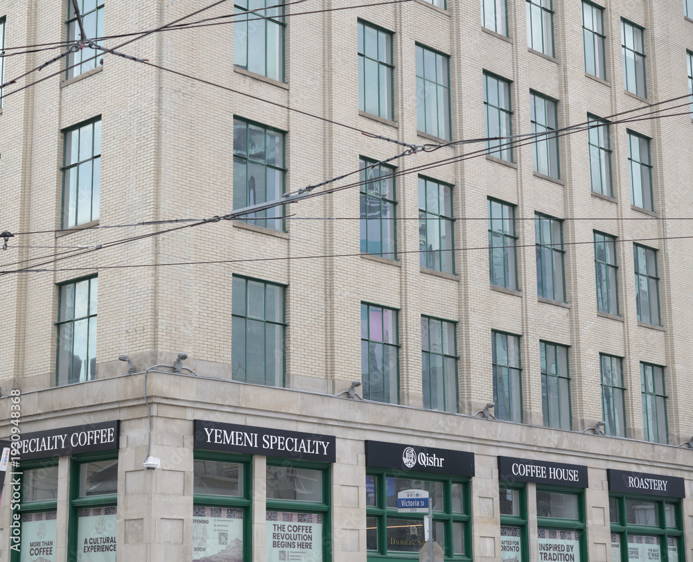 Naklejka premium exterior of 21 Dundas Square, the 1929 wing of the historic Hermant Building, with signage for Qishr coffee shop, Toronto