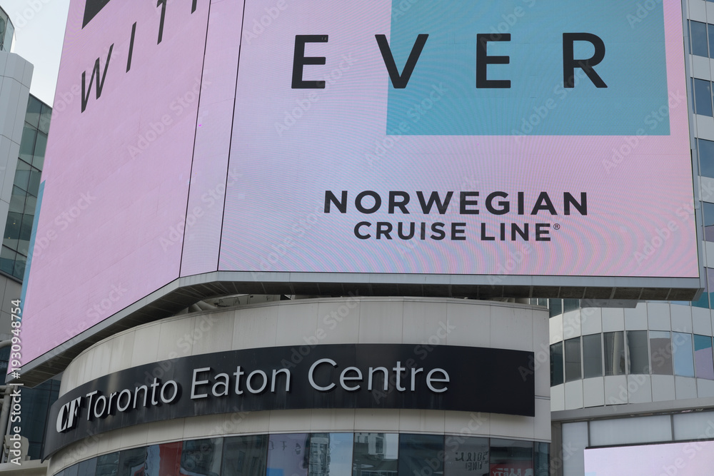 Fototapeta premium Norwegian Cruise Line advertisement for 2026 on electronic display above entrance to CF Toronto Eaton Centre, facing Sankofa Square, Toronto