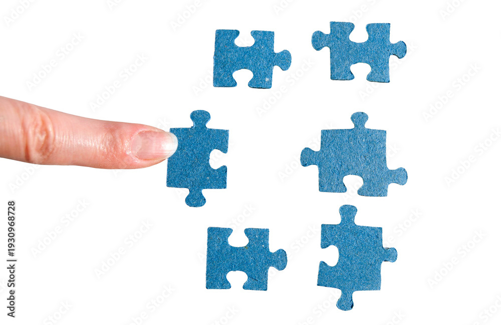 Fototapeta premium A finger adds a blue jigsaw piece. A hand holding a puzzle piece.