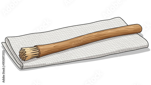 A wooden toothbrush lies on a white towel with a grid pattern, viewed from above