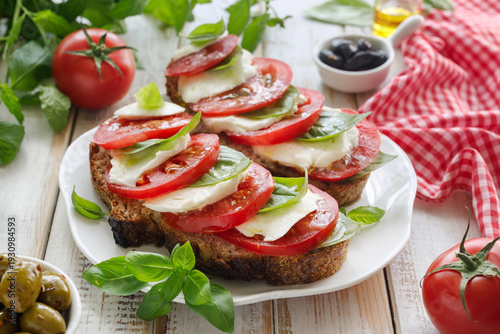 Bruschetta with tomatoes and mozzarella, caprese salad on a white plate, close-up
