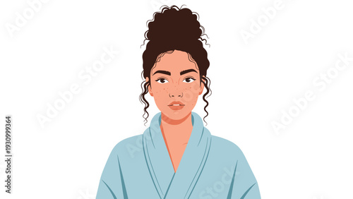Portrait of a beautiful woman with curly hair in a messy bun wearing a light blue bathrobe after her morning skincare.