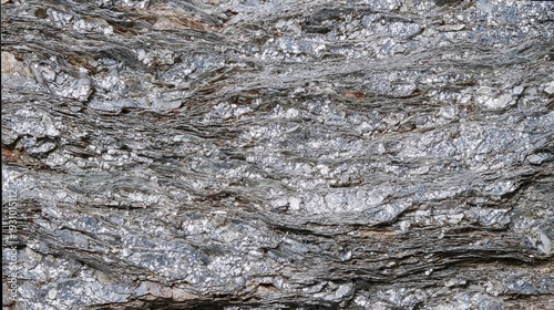 Mica schist texture, flaky shiny layers of silver mica embedded in rock, glittery geological texture