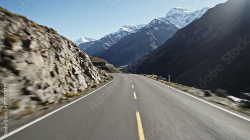 Winding road through vast mountains with snow-capped peaks